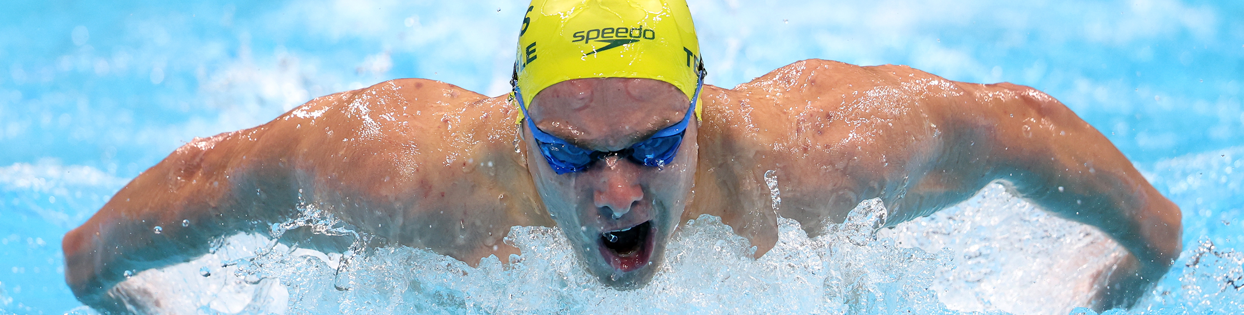 Matt Temple with a swimming cap and goggles on emerging from the water