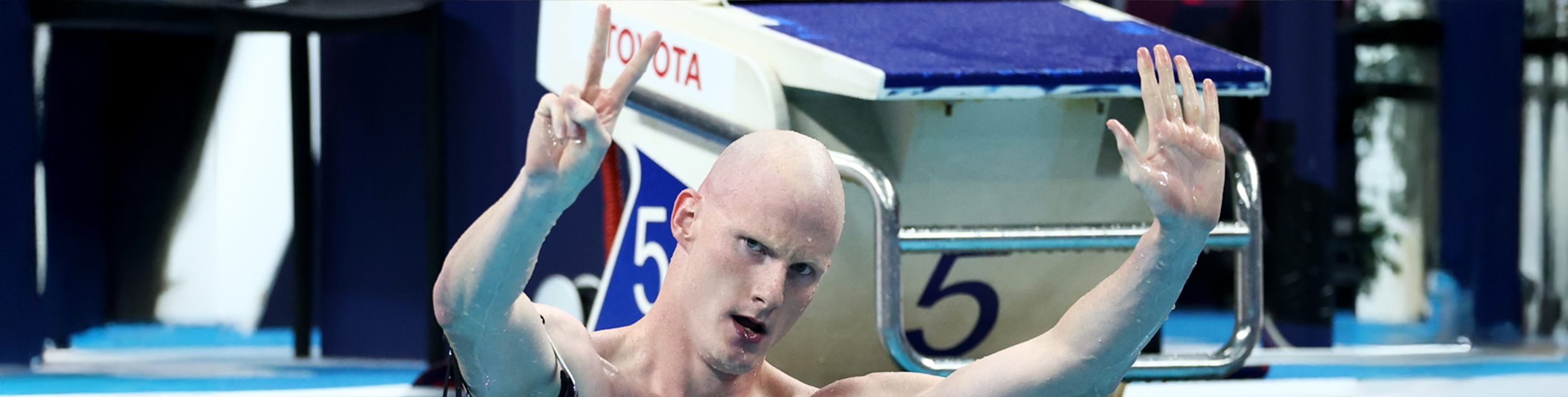 Rowan Crothers holds up seven fingers standing in the pool